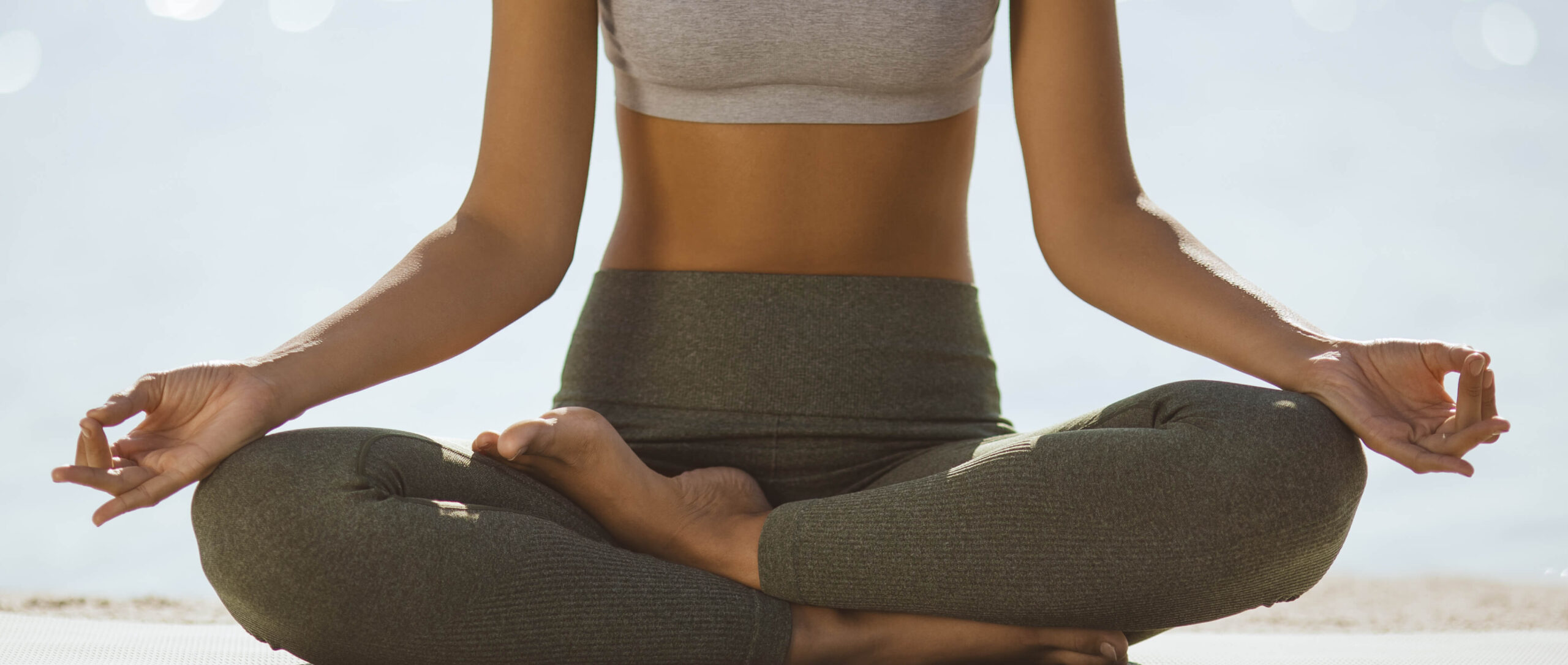 A picture of a woman sitting cross legged in a yoga pose, with her arms resting on her knees
