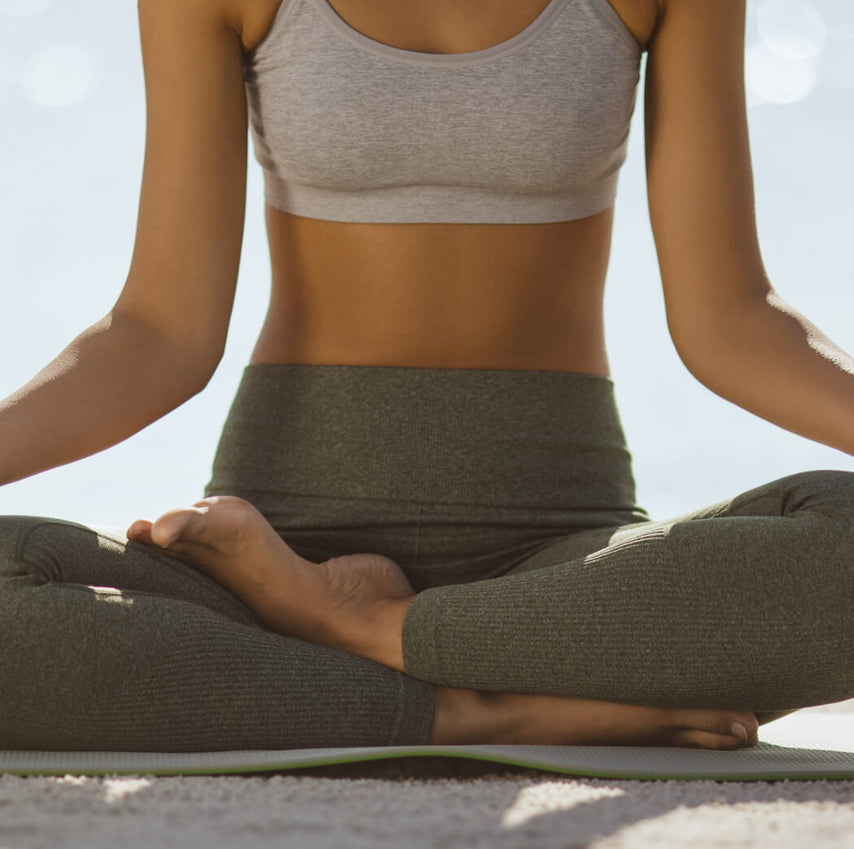 a picture of a woman sitting cross legged in a yoga pose, with her arms resting on her knees