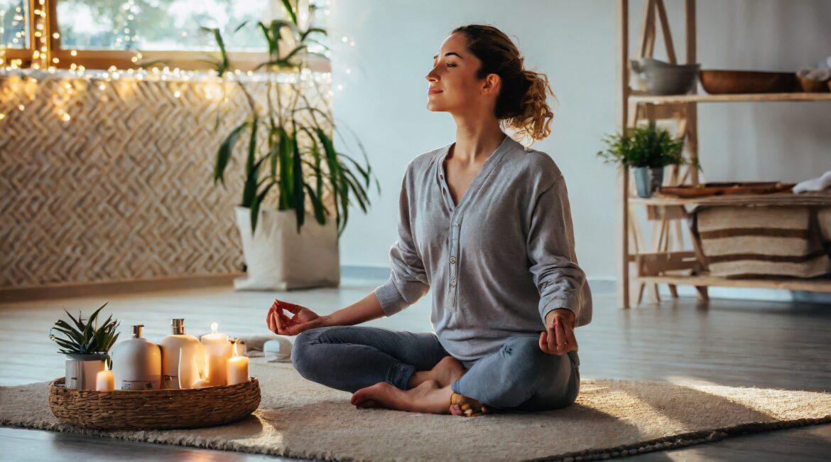 A woman sitting cross legged in a yoga pose, with candles in front of her.